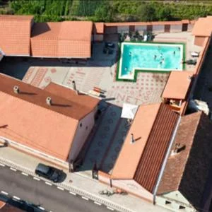Pensiunea văzută de sus, din dronă: acoperișurile de țiglă, curtea pavată și piscina în formă de L