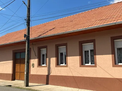Fațada pensiunii spre stradă, cu ferestre albe și acoperiș de țiglă