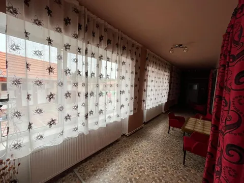 Hol luminos cu perdele albe brodate și fotolii roșii